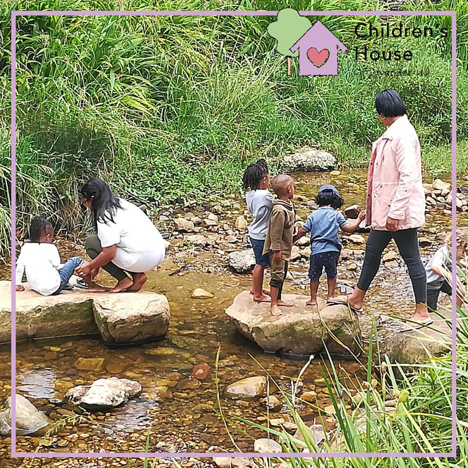 Children and teachers by the Liesbeek Parkway river looking for tadpoles